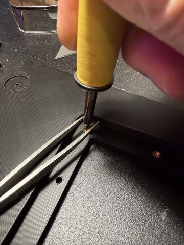 Pushing in brass inserts with a soldering iron and tweezers